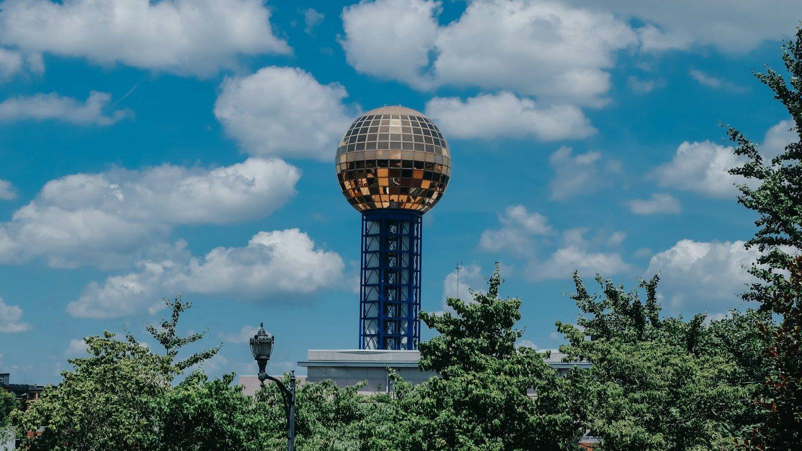 The Sunsphere tower in Knoxville, Tennessee, rising above the treeline against a blue sky